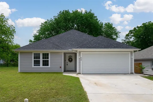 a front view of house with yard and trees in the background