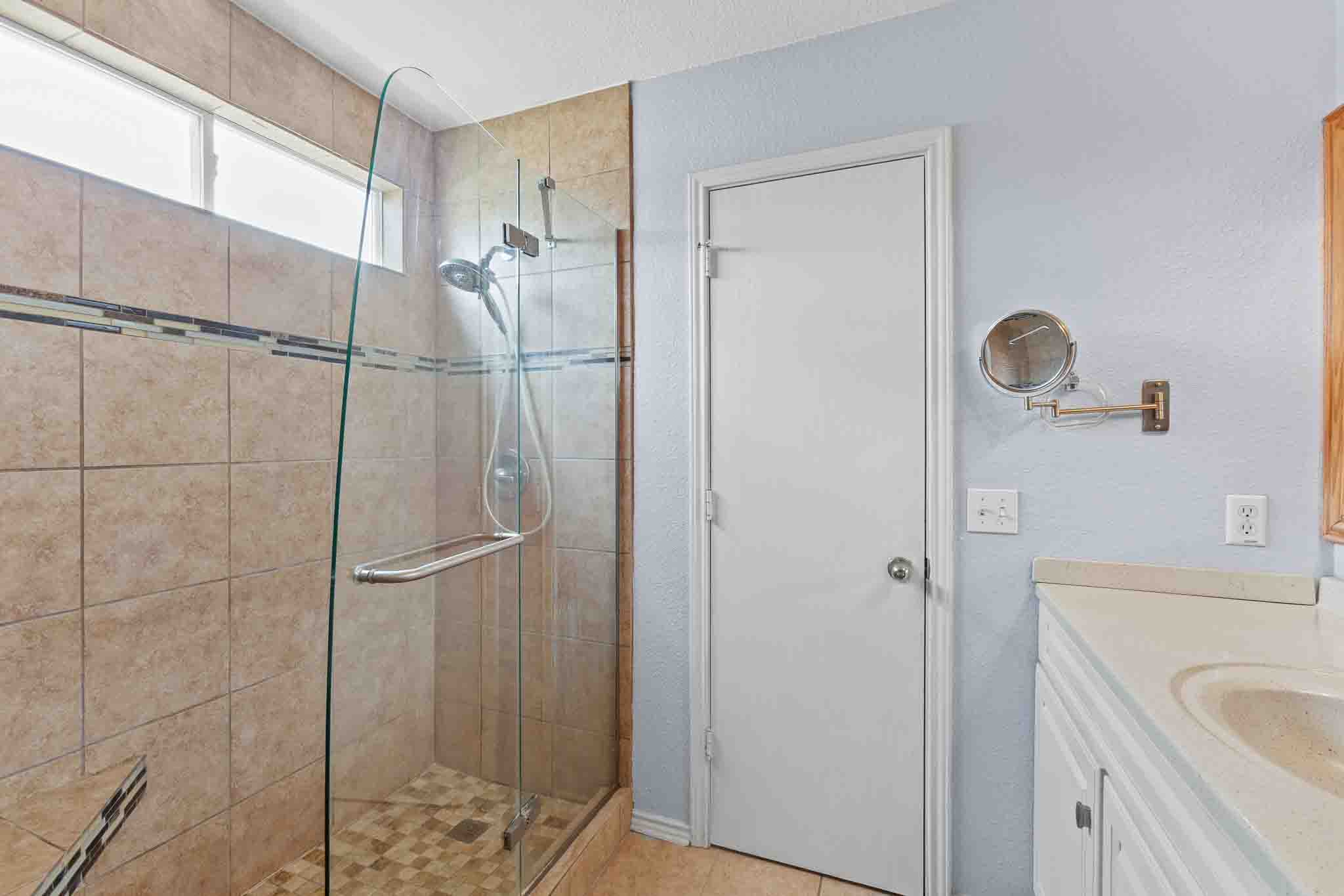 270 Endeavour Kyle, TX 78640 - Photo 14 of 20 The bathroom features a spacious shower with glass enclosure, tile walls, and a mosaic tile floor