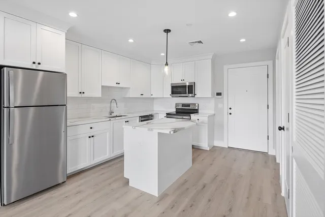 a kitchen with white cabinets and stainless steel appliances