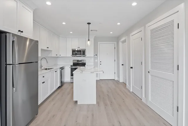 a kitchen with white cabinets and stainless steel appliances