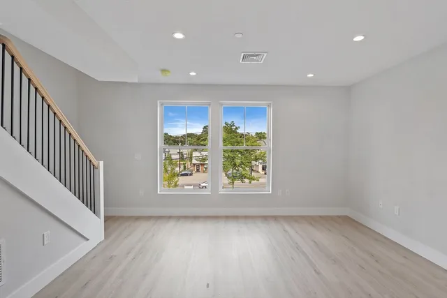 an empty room with wooden floor and windows