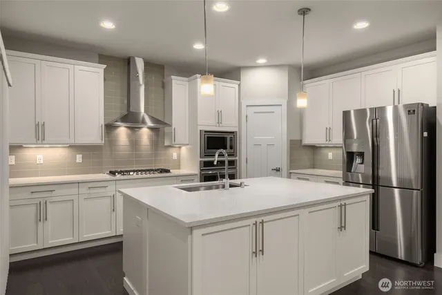 a kitchen with stainless steel appliances a refrigerator and a stove top oven