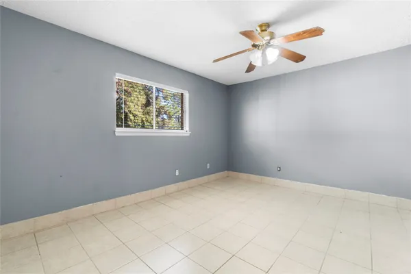 an empty room with a chandelier fan and window
