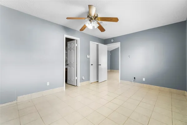 a view of an empty room and chandelier fan