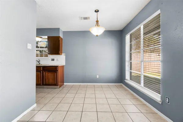 a view of an empty room with a window and kitchen view