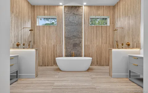 a bathroom with a double vanity sink a mirror and a bathtub