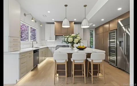 a kitchen with stainless steel appliances kitchen island granite countertop a dining table chairs and white cabinets