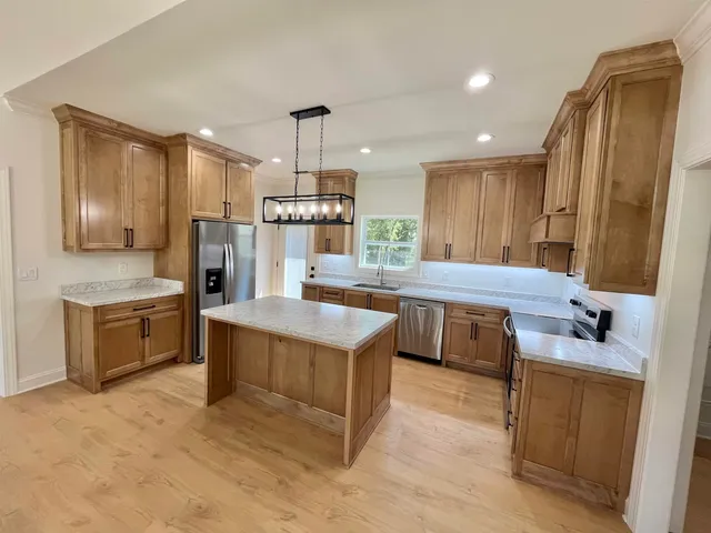 a kitchen with kitchen island granite countertop a sink refrigerator stove and microwave