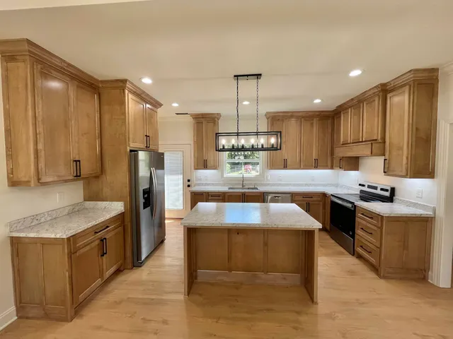 a kitchen with stainless steel appliances granite countertop a stove refrigerator sink and microwave