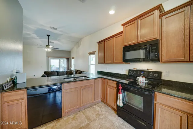 a kitchen with stainless steel appliances granite countertop a sink a stove top oven a counter space and cabinets