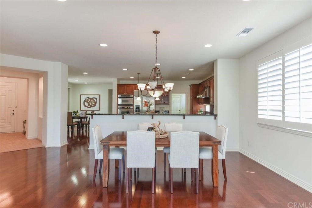 17 Stonegate Irvine, CA 92602 - Photo 17 of 72 a dining room with wooden floor a chandelier a wooden table and chairs