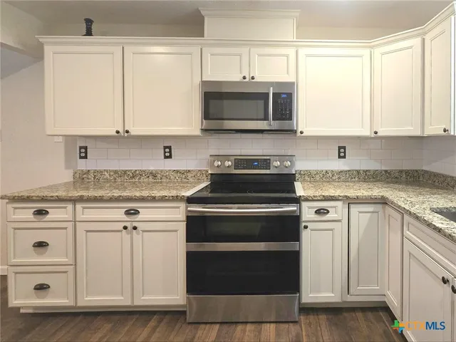 a kitchen with white cabinets and appliances