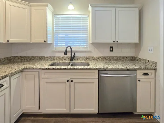 a kitchen with granite countertop white cabinets and a sink