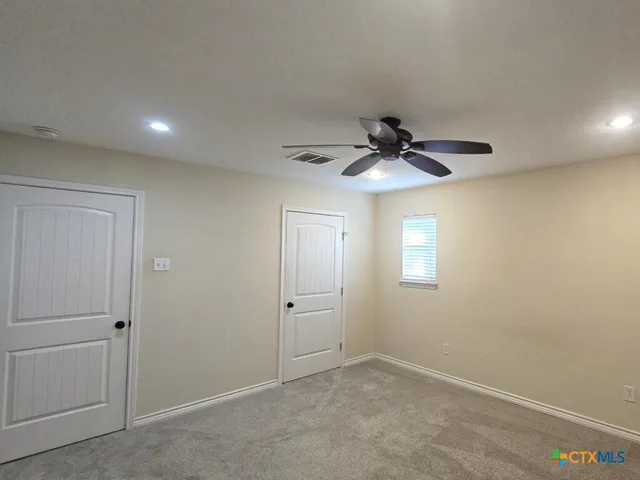 an empty room with a ceiling fan and a window