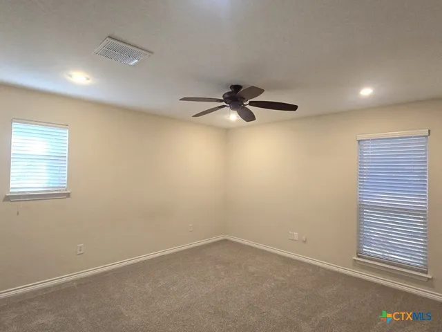 an empty room with a ceiling fan and window