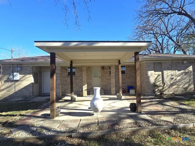 a view of a house with cars park side of road