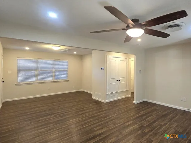 a view of an empty room with wooden floor and a window