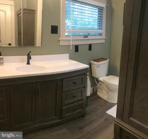 a bathroom with a granite countertop toilet sink and mirror