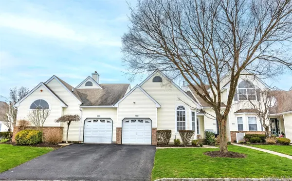 a view of a white house next to a yard with big trees