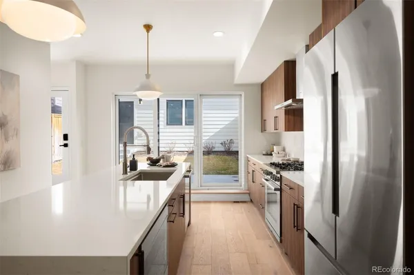 a kitchen with kitchen island granite countertop lots of counter top space a sink refrigerator and cabinets