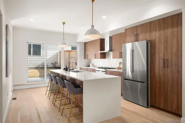 a kitchen with stainless steel appliances a dining table chairs stove and refrigerator