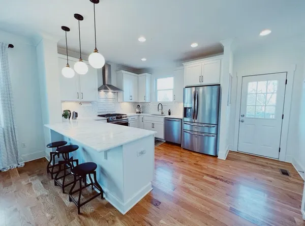 a kitchen with stainless steel appliances granite countertop a sink a stove a refrigerator and island with wooden floor