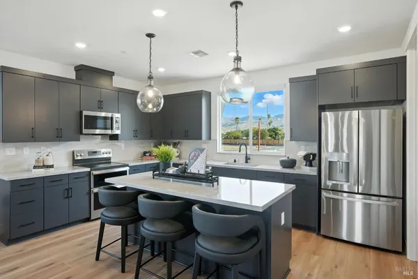 a kitchen with granite countertop a sink appliances a refrigerator and chairs