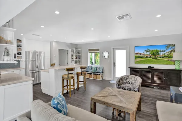 a living room with furniture a flat screen tv and kitchen view