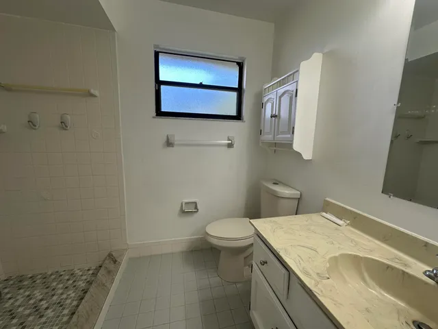 a bathroom with a granite countertop toilet and a sink