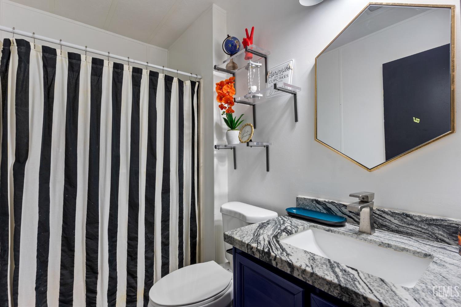 Undisclosed Address Bakersfield, CA 93306 - Photo 7 of 27 a bathroom with a granite countertop toilet sink and mirror