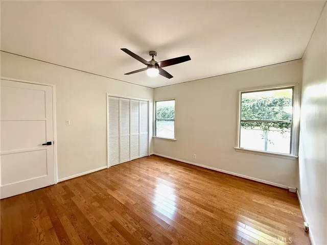 a view of empty room with wooden floor and fan