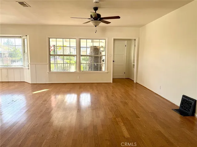 a view of empty room with wooden floor and fan