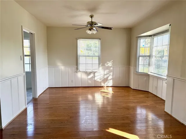 an empty room with wooden floor chandelier and windows