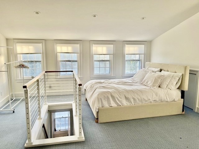 76 Orange Street Nantucket, MA 02554 - Photo 23 of 34 a spacious bedroom with a bed and a fireplace