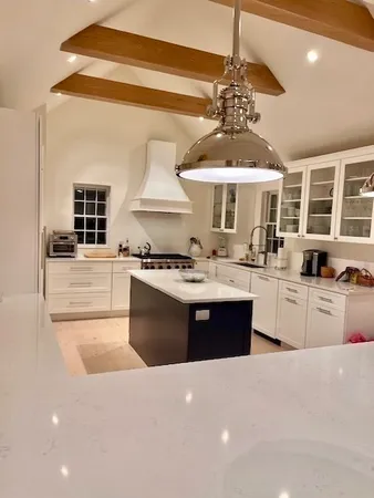 a large kitchen with stainless steel appliances a large counter top a stove and a chandelier