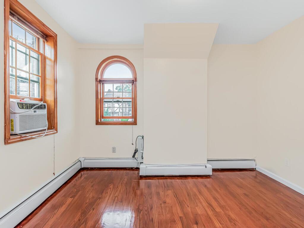 57-07 146th Street Queens, NY 11355 - Photo 9 of 19 an empty room with wooden floor and windows