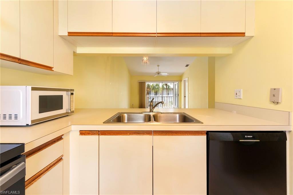 1915 Courtyard Way, Unit G202 Naples, FL 34112 - Photo 4 of 22 Kitchen with black dishwasher, white microwave, range, light countertops, and white cabinets