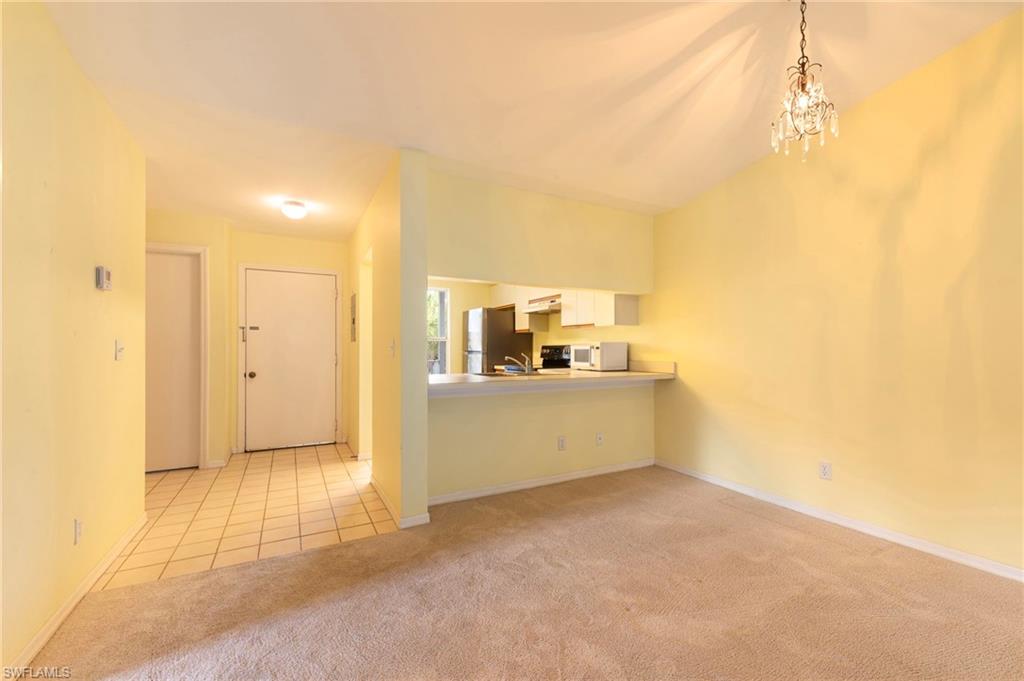 1915 Courtyard Way, Unit G202 Naples, FL 34112 - Photo 5 of 22 Unfurnished living room featuring light carpet and suspended lighting