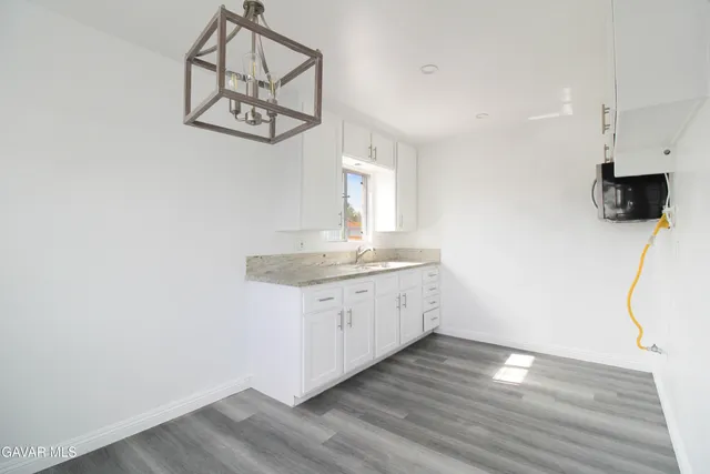 a room with kitchen island a wooden floor and white walls