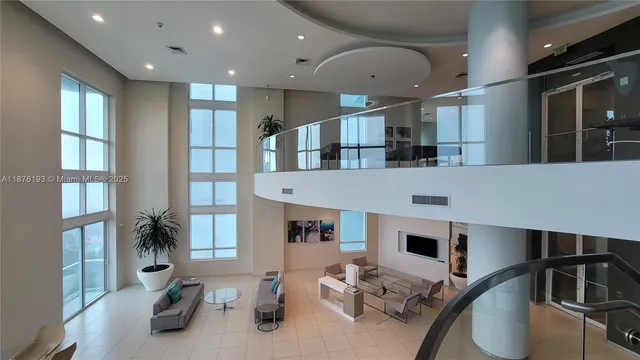 a living room with stainless steel appliances furniture a rug and a large window