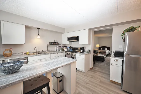 a kitchen with a refrigerator a stove a sink dishwasher and wooden cabinets with wooden floor