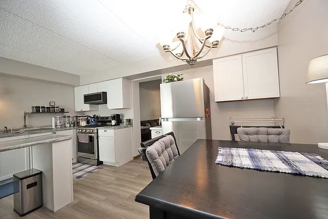 a kitchen with stainless steel appliances granite countertop a sink dishwasher a stove top oven a dining table and chairs with wooden floor