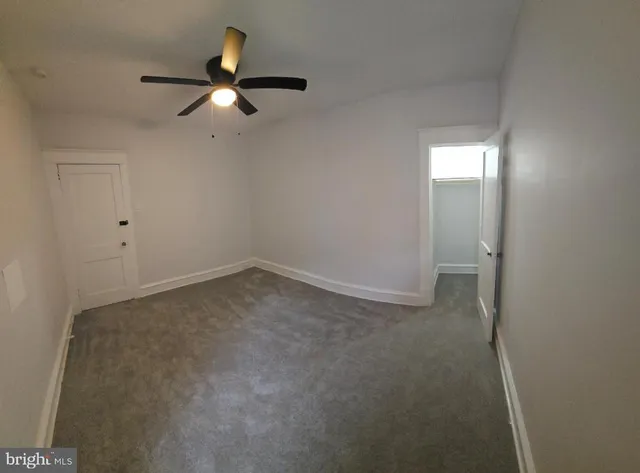 an empty room with closet and a chandelier fan