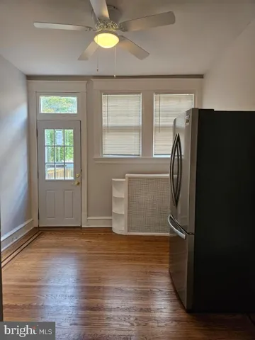a view of a refrigerator in kitchen and an empty room with wooden floor