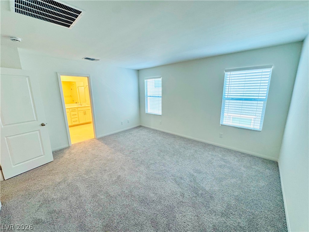 9249 Innot Avenue Las Vegas, NV 89148 - Photo 14 of 24 A spacious, naturally illuminated room featuring plush carpeting and a clear view into a functional bathroom space.