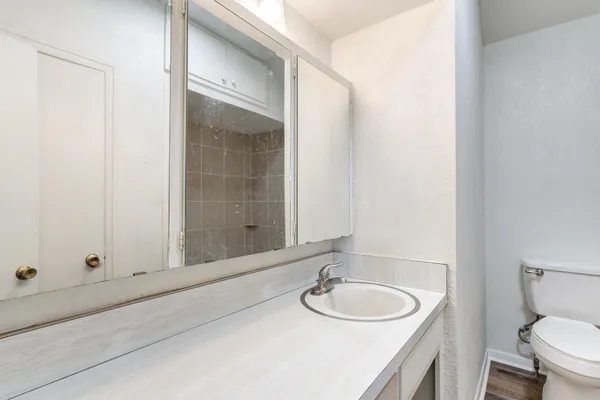 a bathroom with a granite countertop sink toilet and mirror