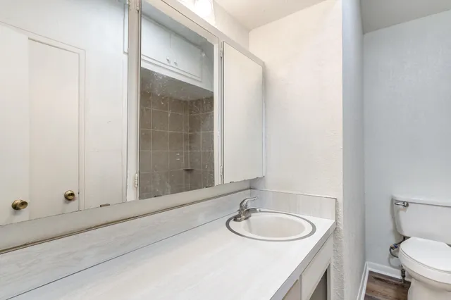 a bathroom with a granite countertop sink toilet and mirror
