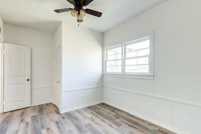an empty room with a window and a ceiling fan