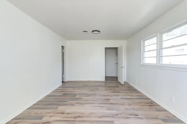 a view of an empty room with wooden floor and a window