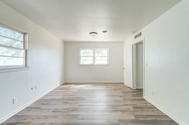 an empty room with wooden floor and windows